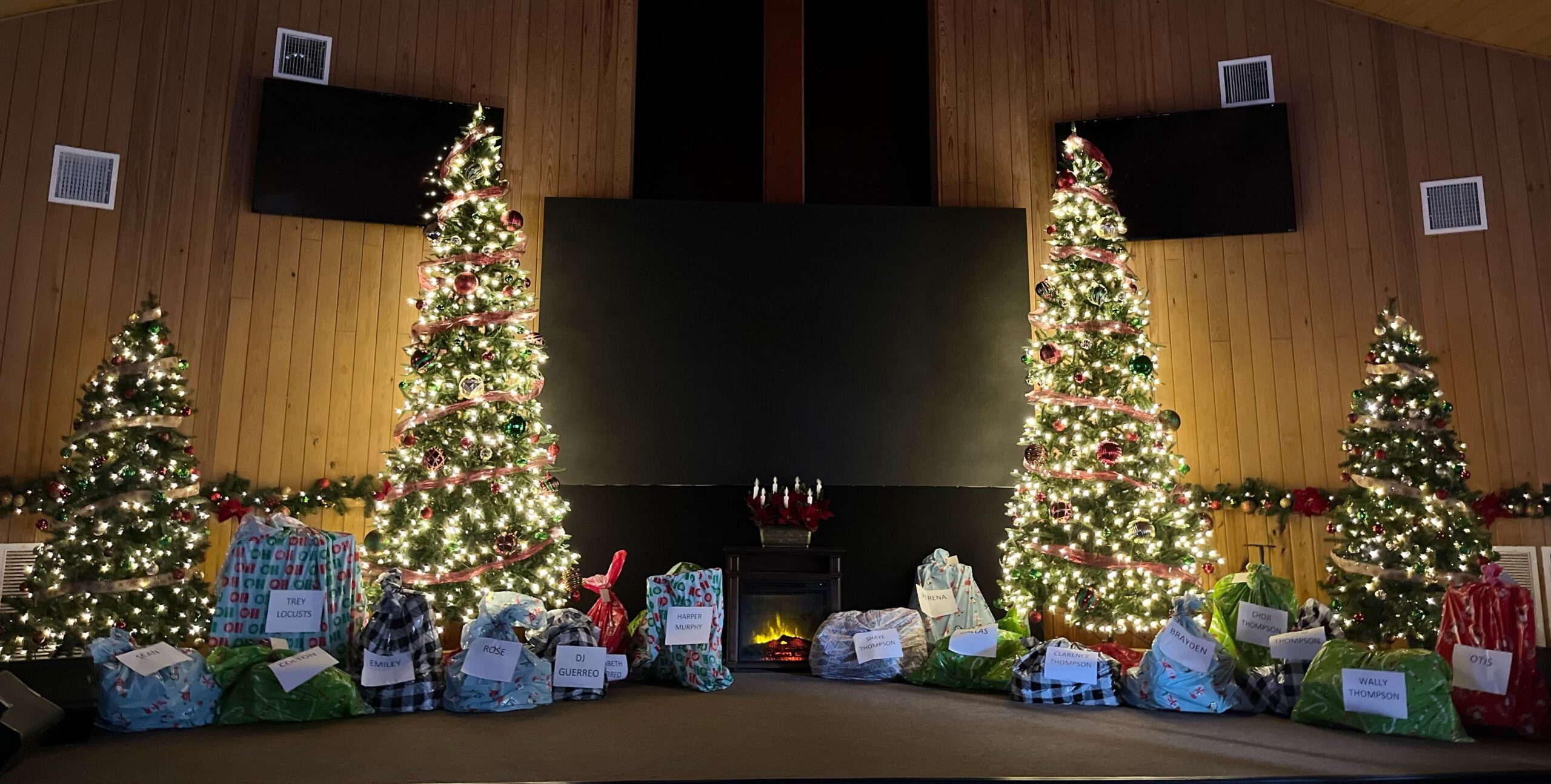 Large collection of Christmas gifts in church with holiday decorations.