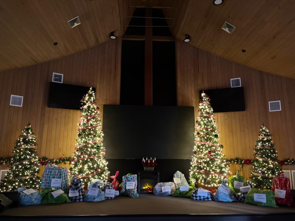 Large collection of Christmas gifts in church with holiday decorations.